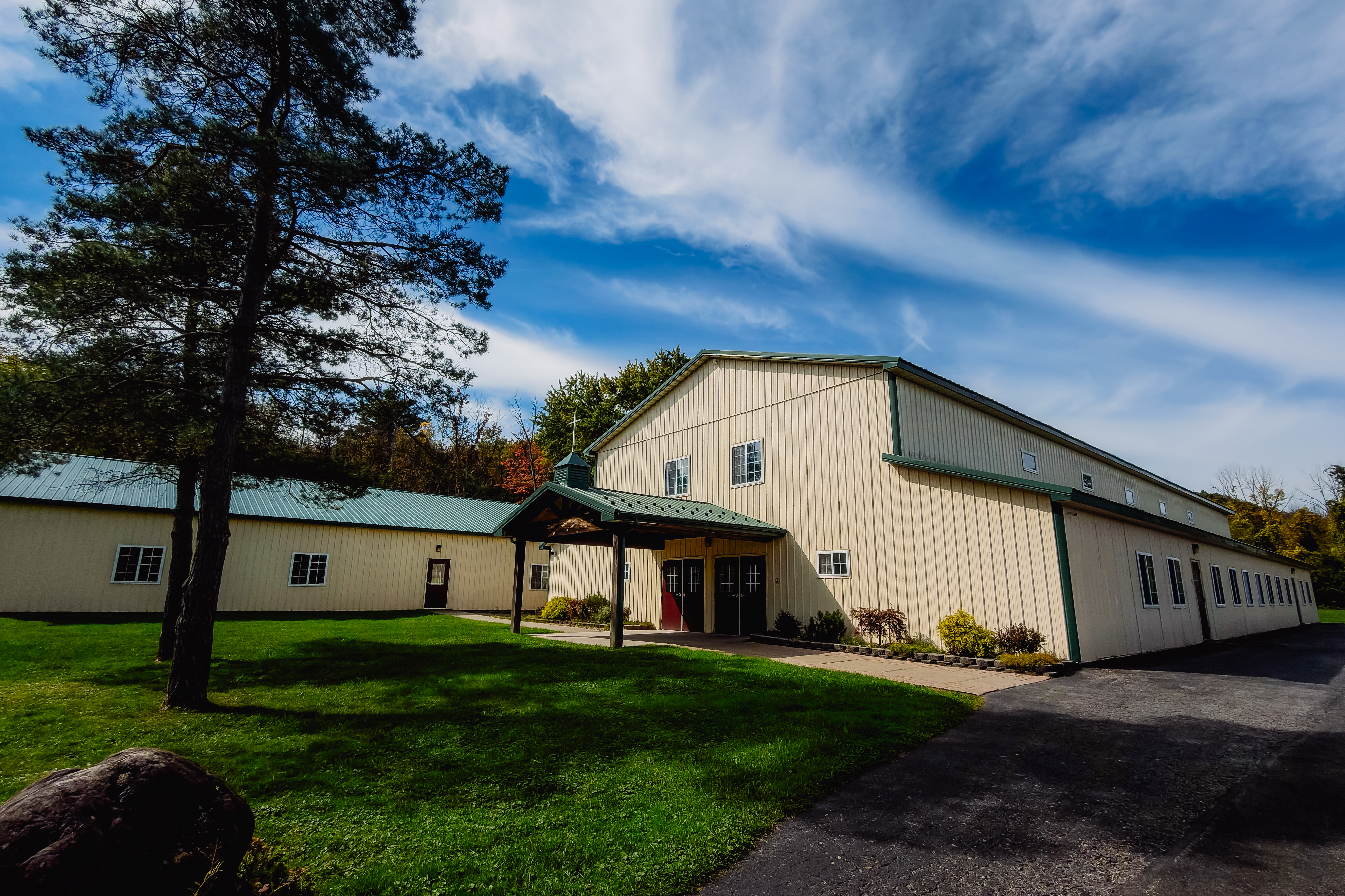 New Life Assembly of God church building exterior with steeple and autumn trees
