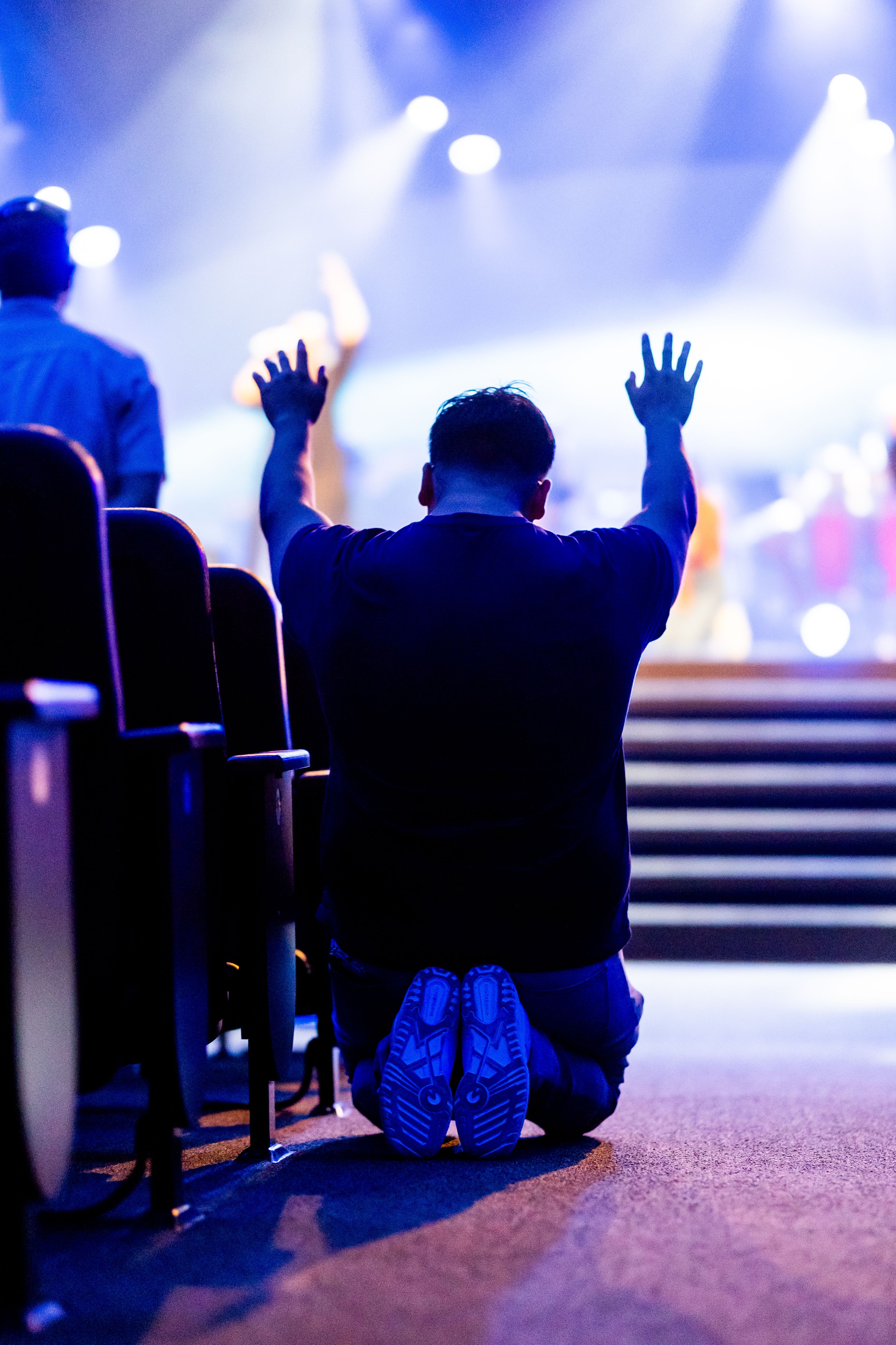 A man and woman praying with hands raised during worship at New Life